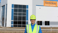 Founder Adam Greenberg wearing a hard hat in front of new headquarters in Green Oaks, Illinois